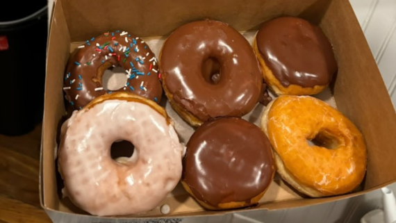 A tempting box from one of the best donut shops: six donuts&mdash;three with chocolate glaze, one with white glaze and colorful sprinkles, one classic white glazed, and one plain glazed delight.