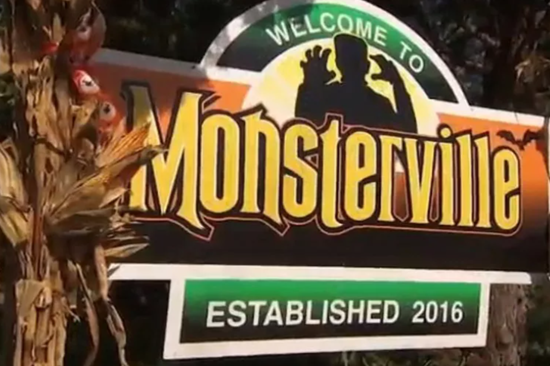 A sign reads "Welcome to Monsterville, Established 2016," with a monster silhouette and bats; dried cornstalks decorate the side—setting the scene in one of the best trick or treat towns in America.