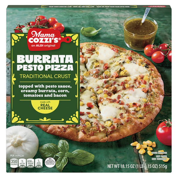 Mama Cozzi's Burrata Pesto Pizza box showing a pizza topped with pesto sauce, burrata, corn, tomatoes, and bacon. Fresh vegetables and a wedge of cheese are arranged next to the pizza.