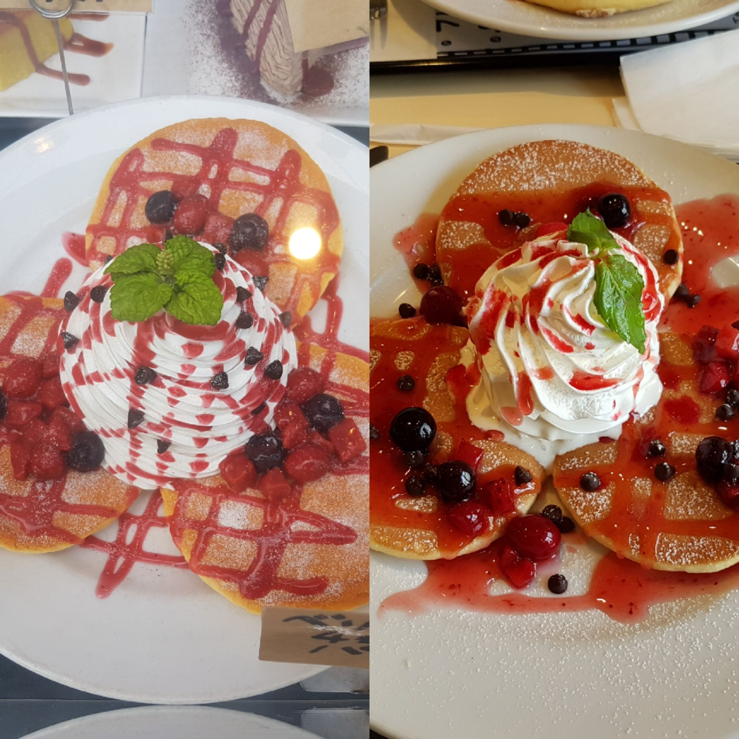 Two plates of pancakes topped with whipped cream, mixed berries, berry sauce, and mint leaves, dusted with powdered sugar, served on white plates.