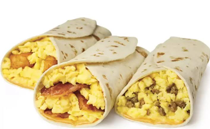 Three breakfast burritos filled with scrambled eggs. The first contains hash browns, the second contains bacon, and the third contains sausage. Each is wrapped in a flour tortilla and placed on a white surface.