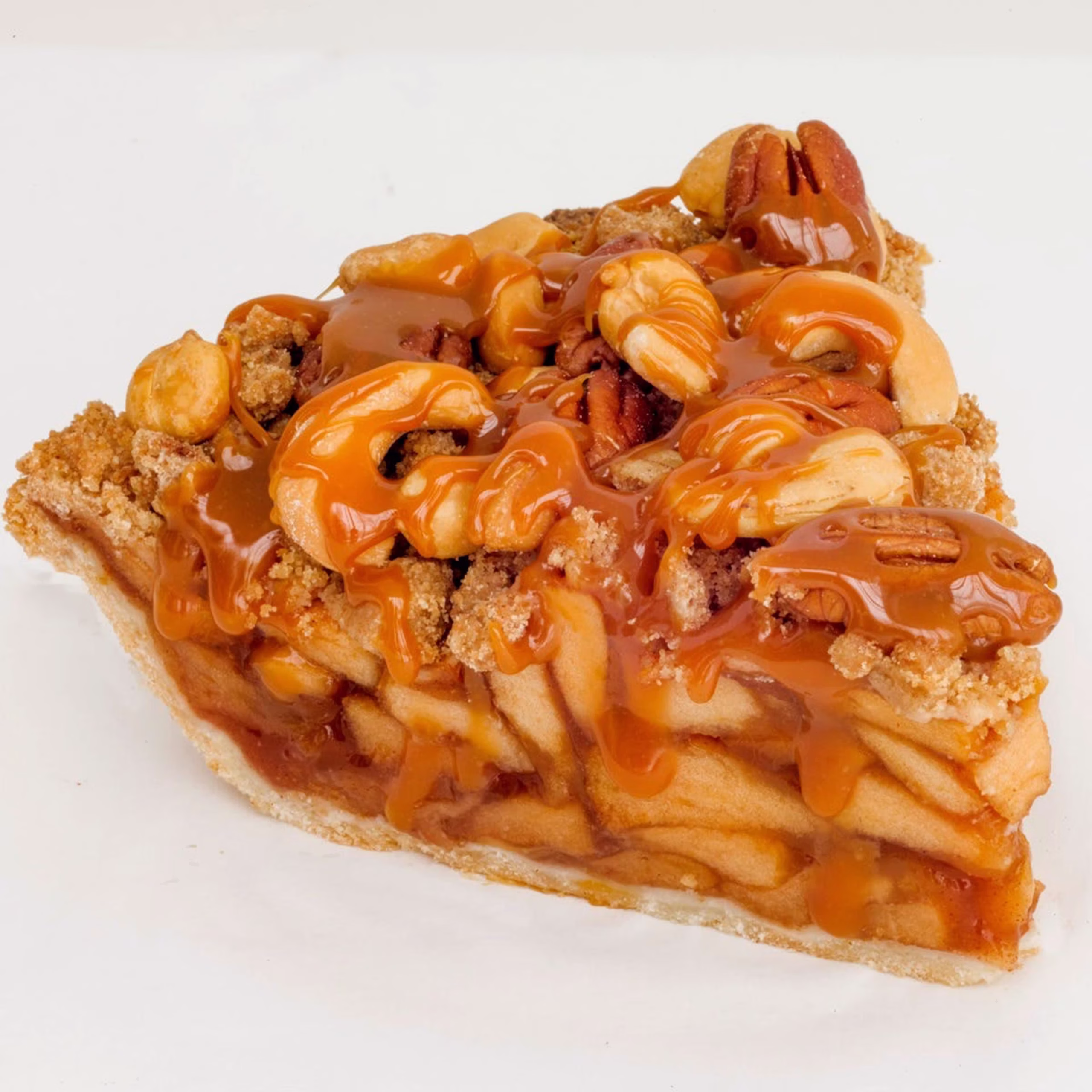 A slice of apple pie topped with caramel sauce, mixed nuts, and crumbly streusel makes this one of the most tempting apple pies, set against a white background.