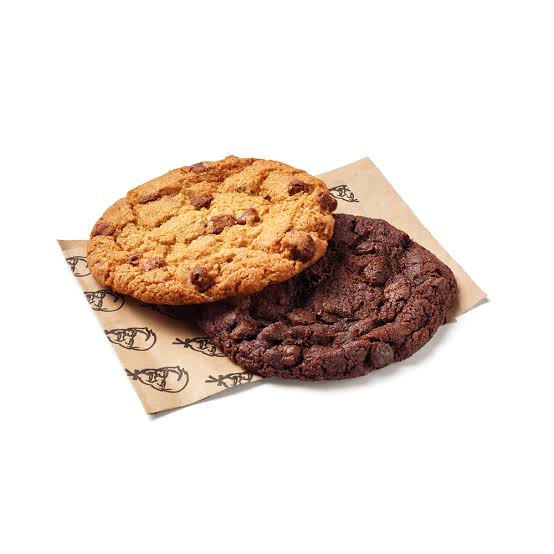 Two large cookies, one chocolate chip and one double chocolate, placed on brown KFC-branded paper against a white background.