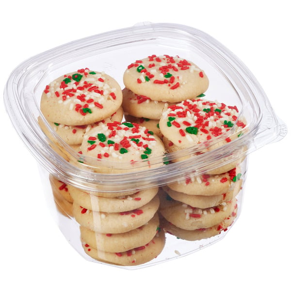 A clear plastic container filled with round, festive sugar cookies topped with red, green, and white sprinkles.