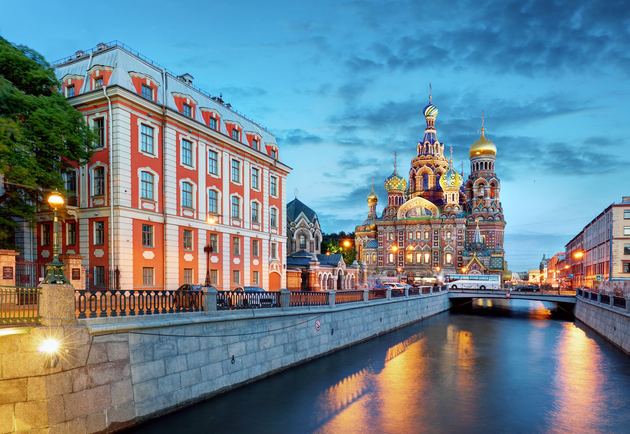 Colorful Church of the Savior on Spilled Blood and historic buildings line a canal in Saint Petersburg, Russia—one of the world’s most captivating travel destinations—at sunset, with stunning reflections shimmering on the water.