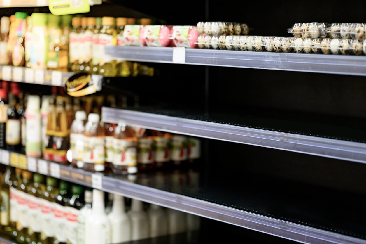 Grocery store shelves with only a few cartons of quail eggs left, surrounded by bottles of oil and vinegar. The shelves appear mostly empty.