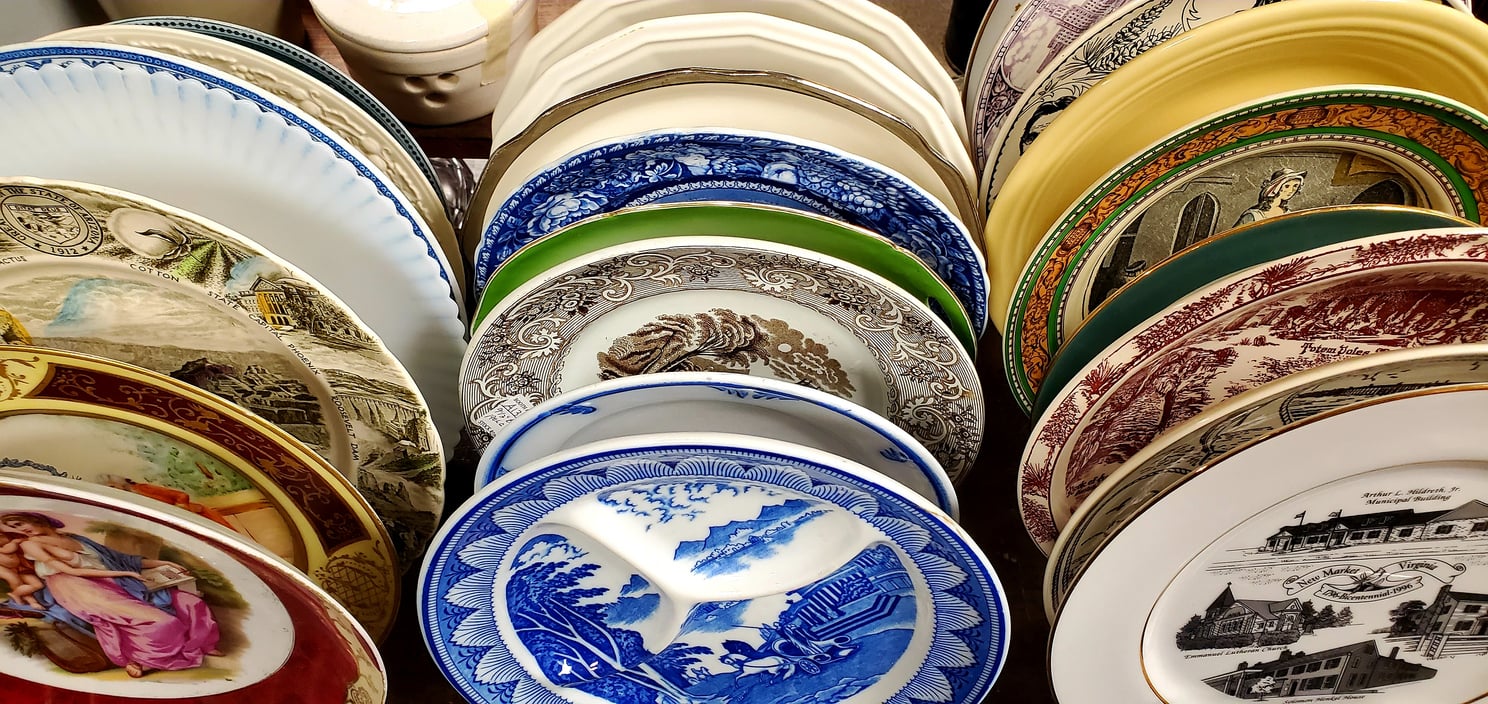 A collection of vintage, decorative plates—timeless kitchen items in various colors and patterns—arranged vertically on a dish rack.