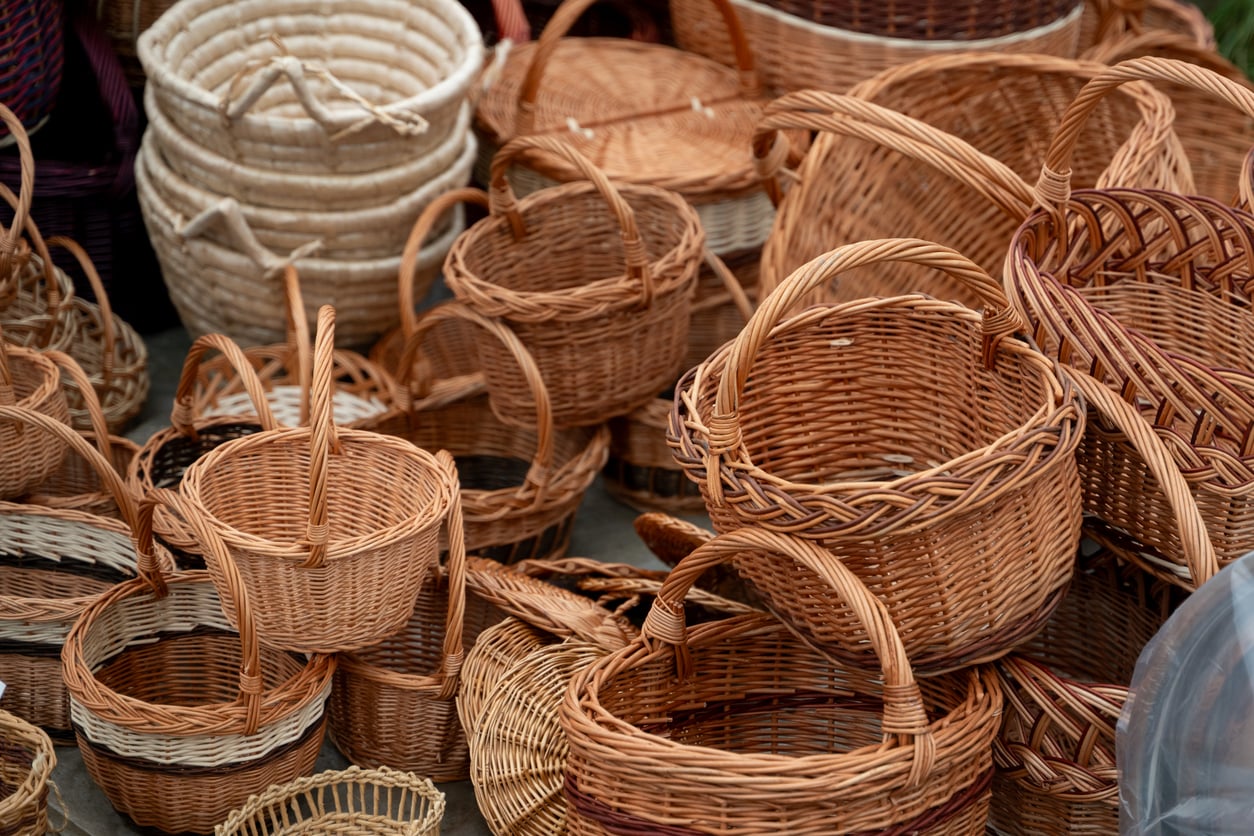 A variety of woven wicker baskets, reminiscent of those beloved by Middle-Class Moms in the 80s and 90s, are stacked and arranged closely together, showcasing their natural brown and beige colors in an inviting display of nostalgia.