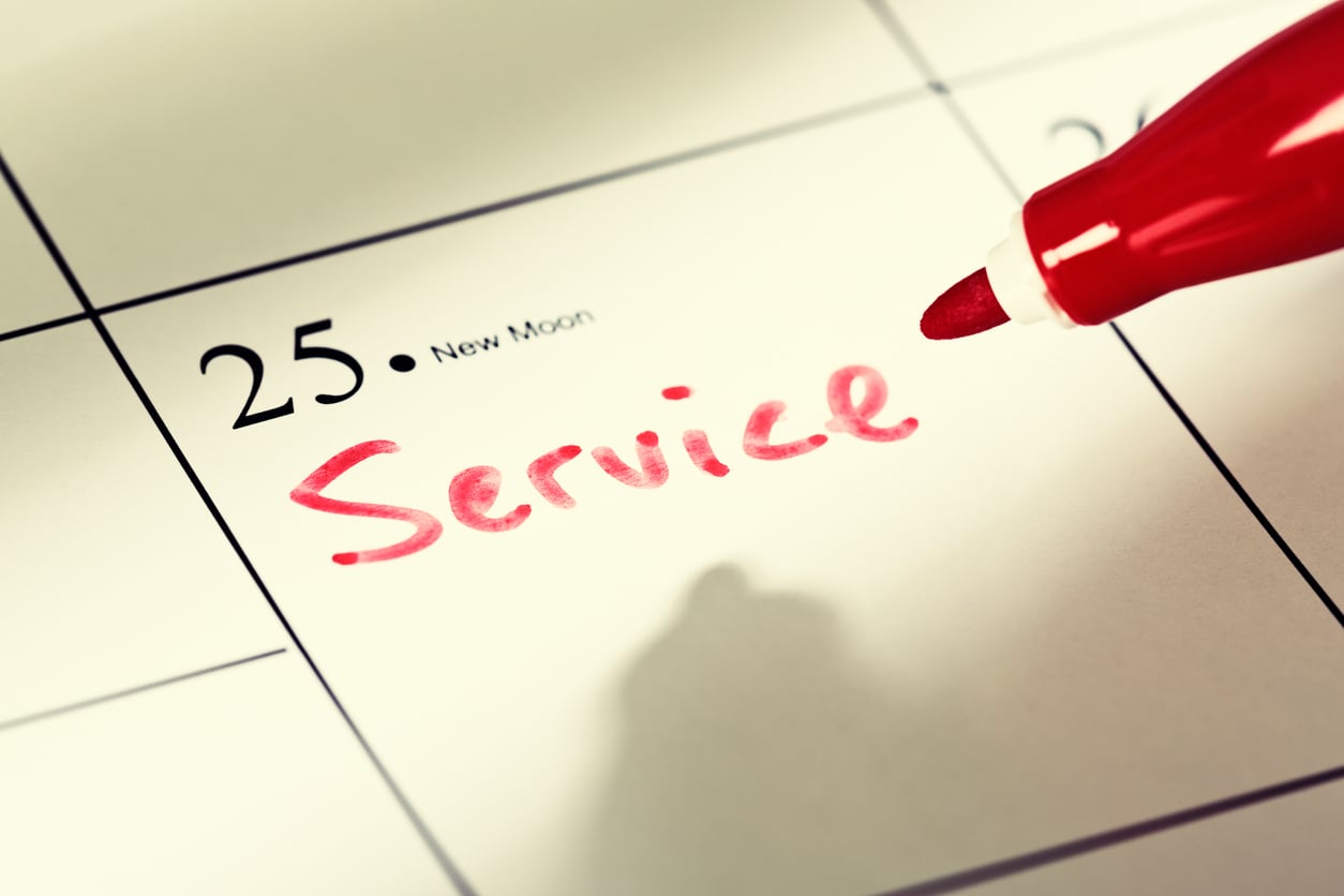 A close-up of a calendar showing the 25th marked with "Service" in red marker, hinting at car maintenance hacks. A red pen sits at the top right, and "New Moon" is also noted on the date.
