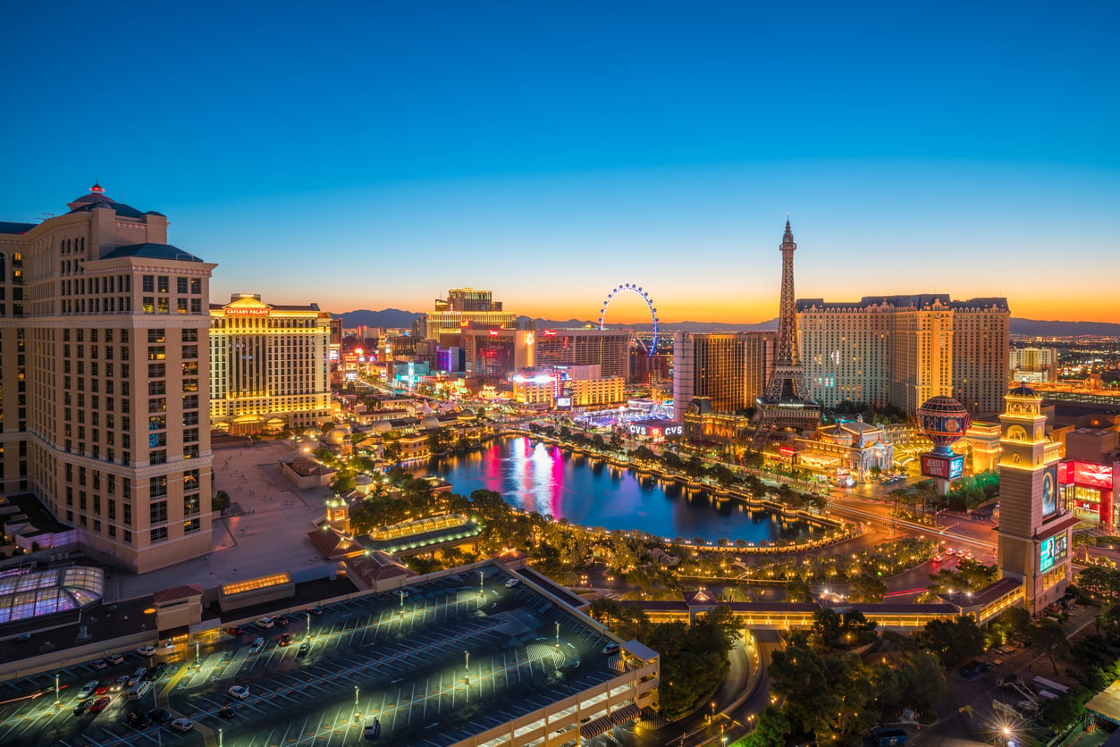 Aerial view of the Las Vegas Strip at sunset, featuring bright lights, hotels, casinos, the Bellagio fountain, and the High Roller Ferris wheel against a colorful sky—one of the world’s most iconic travel destinations.