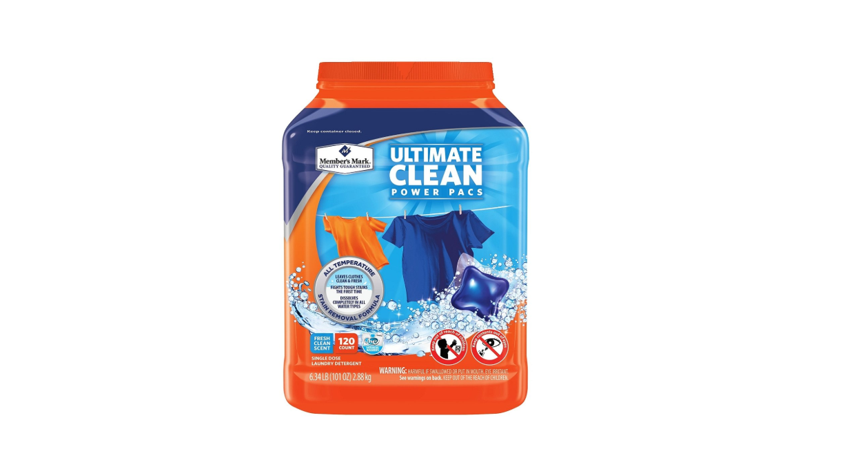 A container of Member's Mark Ultimate Clean Power Pacs laundry detergent with a blue and orange label, images of colorful clothes, and warning symbols on the front.