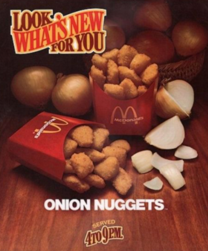 Vintage McDonald's ad with boxes of Onion Nuggets, whole and sliced onions, and bold text saying “Look! What's New For You. Onion Nuggets. Served 4 to 9 PM.” Nuggets are in red McDonald's containers.