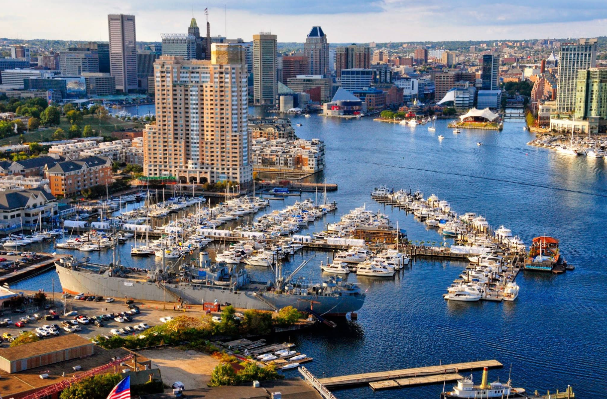 Aerial view of Baltimore’s Inner Harbor, one of the city’s top destinations, with boats docked at marinas, tall buildings in the background, and a historic ship near the waterfront.