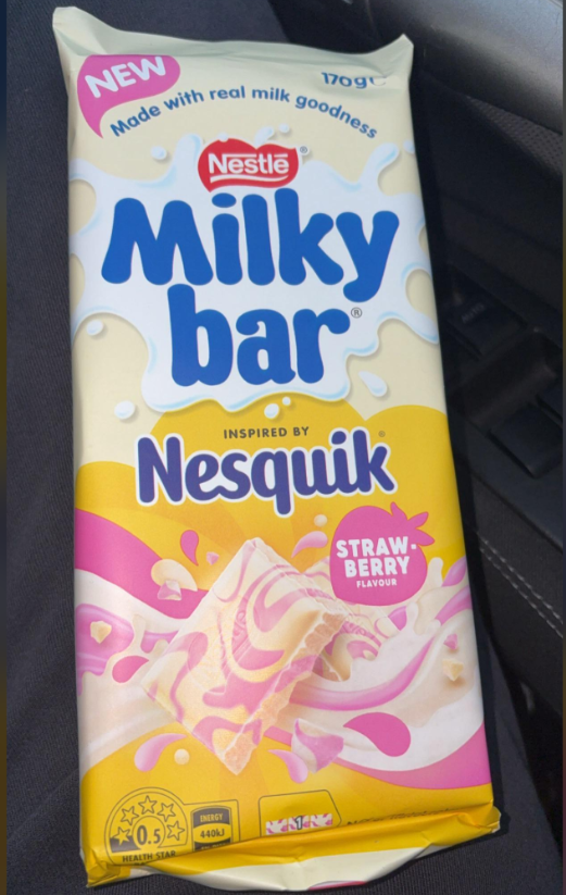 A 170g Nestlé Milkybar inspired by Nesquik strawberry flavor, with swirls of pink and white chocolate, shown in its packaging. The label highlights "Made with real milk goodness.