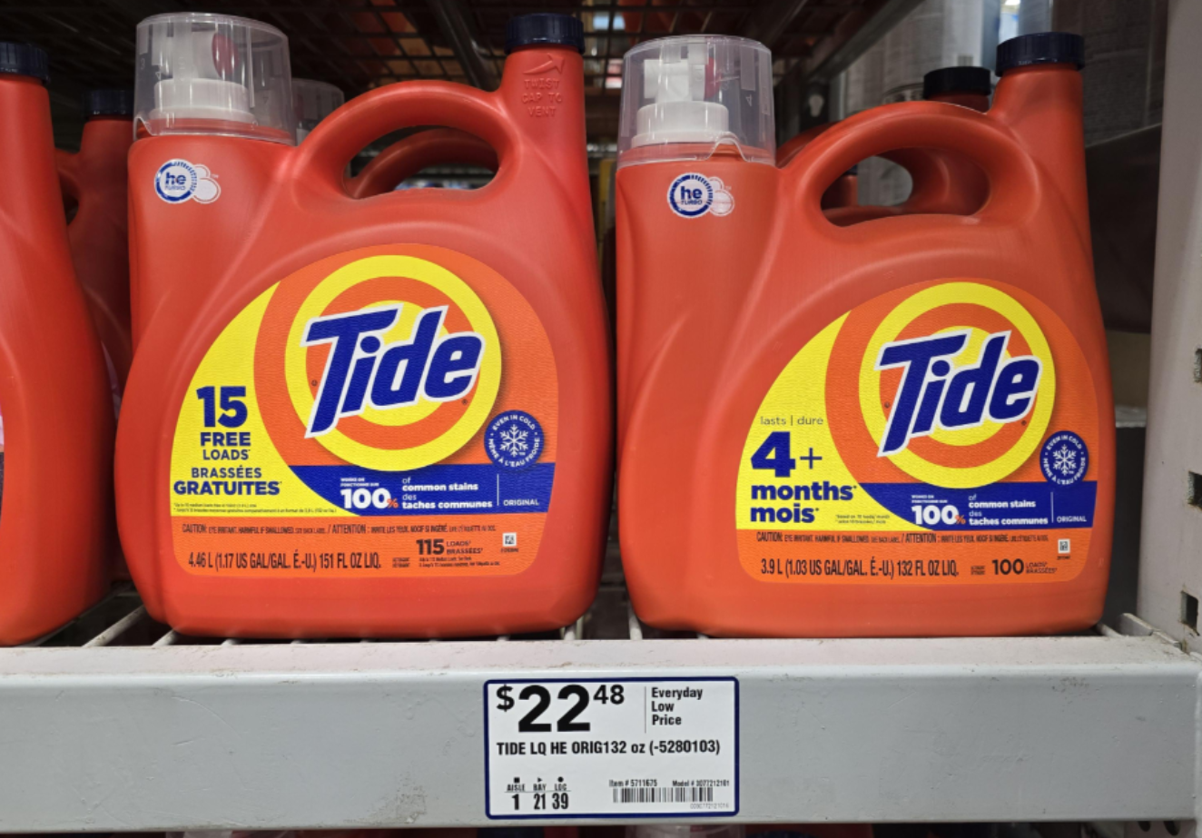 Two large orange bottles of Tide laundry detergent on a store shelf, labeled for 15 free loads and 4+ months of use. Price tag below shows $22.48 for a 4.43 L bottle, highlighting the trend visible in many photos of shrinking products on store shelves today.