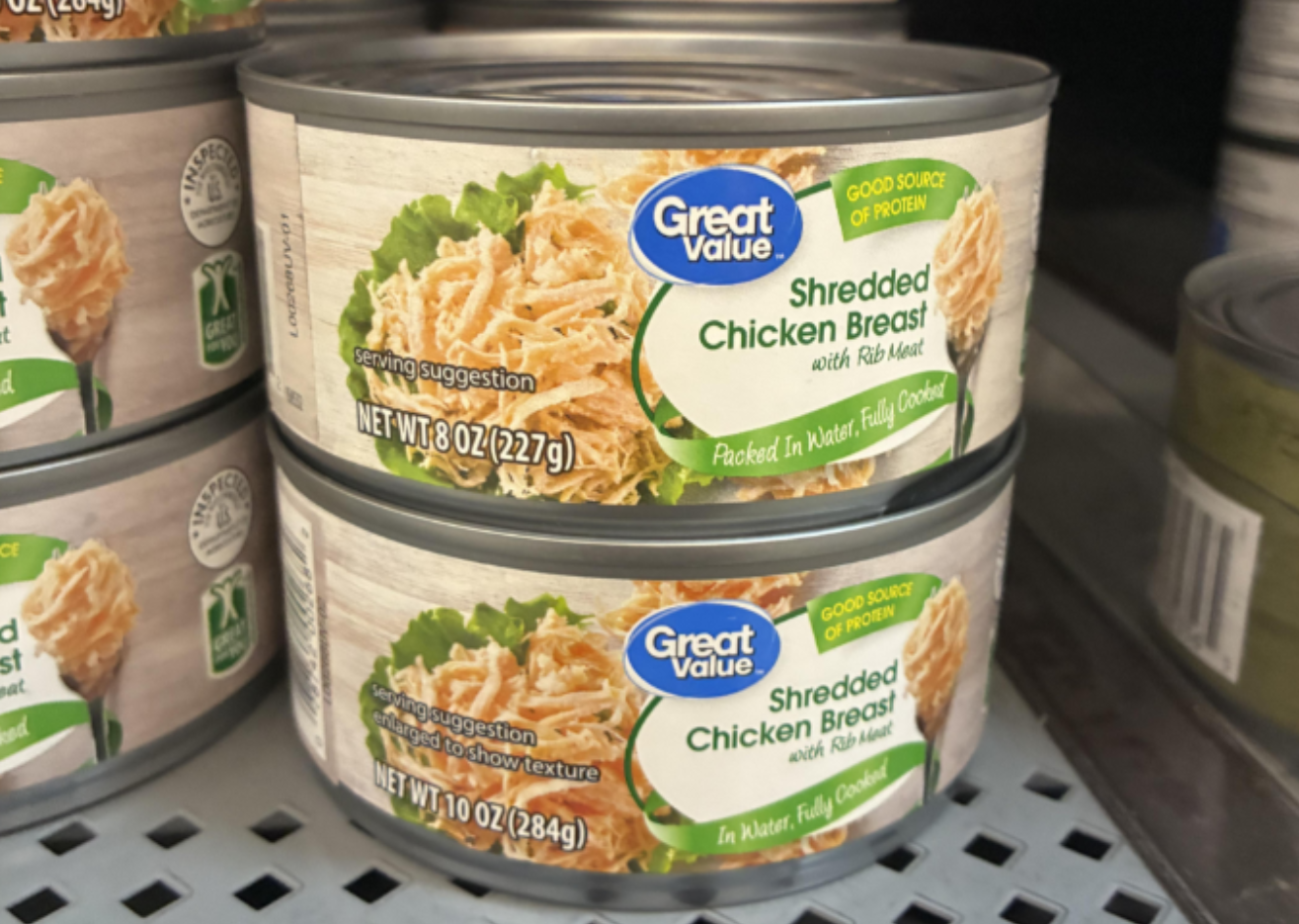 Two cans of Great Value Shredded Chicken Breast with Rib Meat are stacked on a store shelf. The labels show an image of shredded chicken and highlight it as a good source of protein, making them a relevant example for those seeking photos of shrinking products.