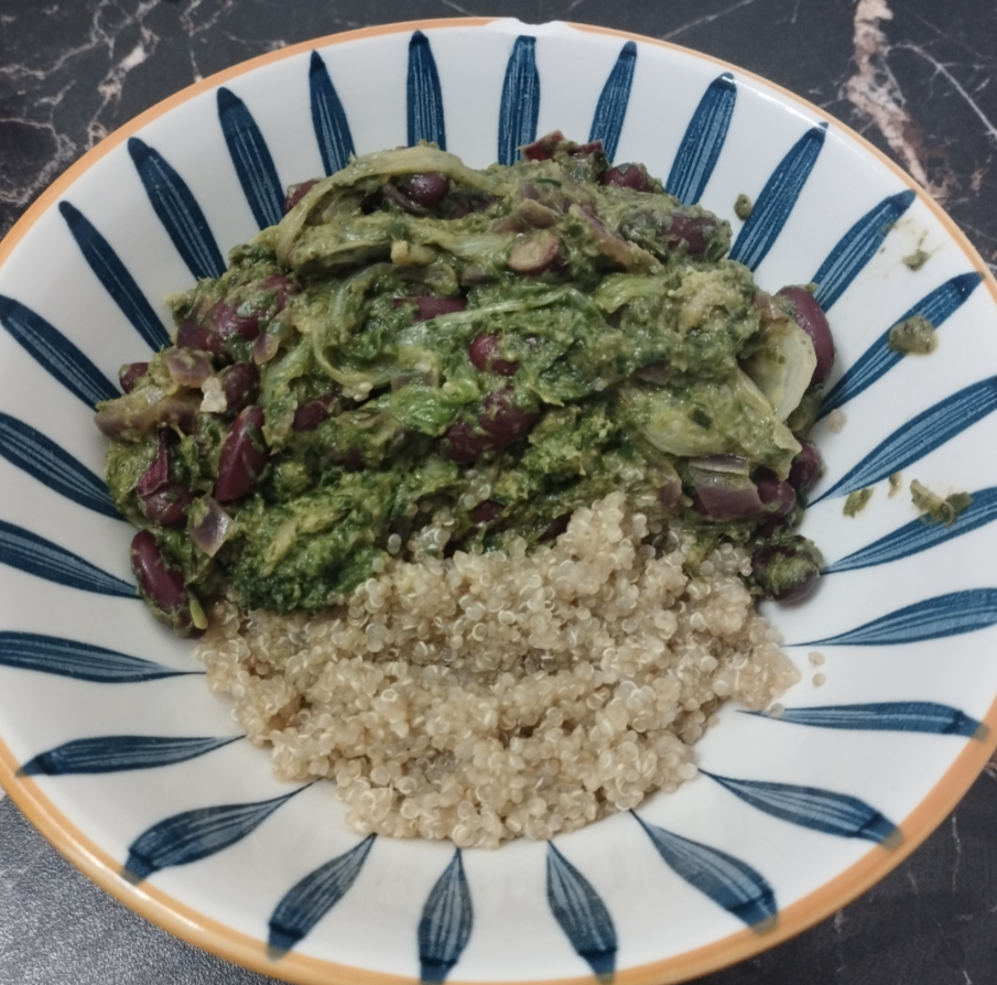 A bowl with cooked quinoa at the bottom and a green vegetable and red kidney bean stew on top, served in a patterned bowl on a dark marble surface—a comforting meal that proves you don’t need any hilarious cooking disasters to enjoy delicious, home-cooked food.