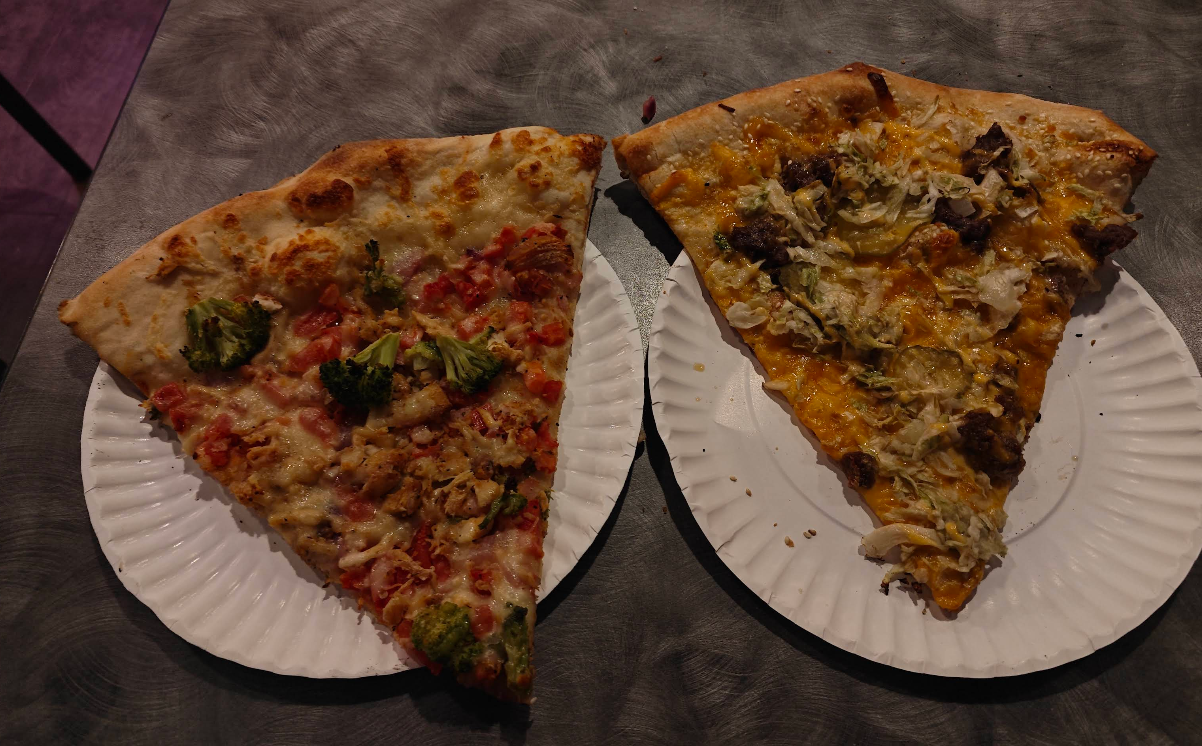 Two large, quality slices of pizza for cheap sit on white paper plates on a gray table. The left slice has broccoli, tomato, and chicken, while the right features beef, onions, and a generous melted cheese topping.