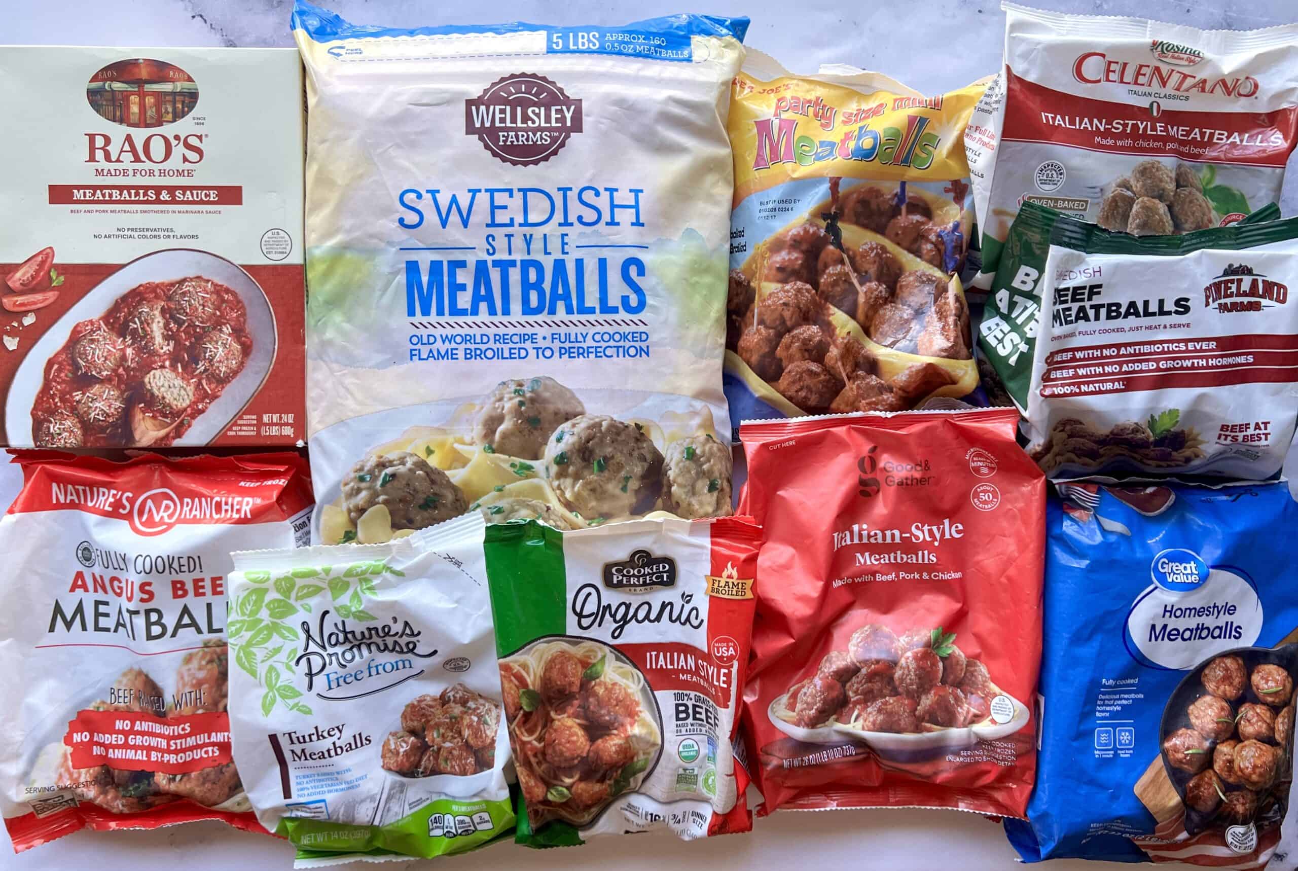 Assorted packages of frozen meatballs of various brands and styles arranged in rows on a white surface, showing different colors, flavors, and packaging designs.