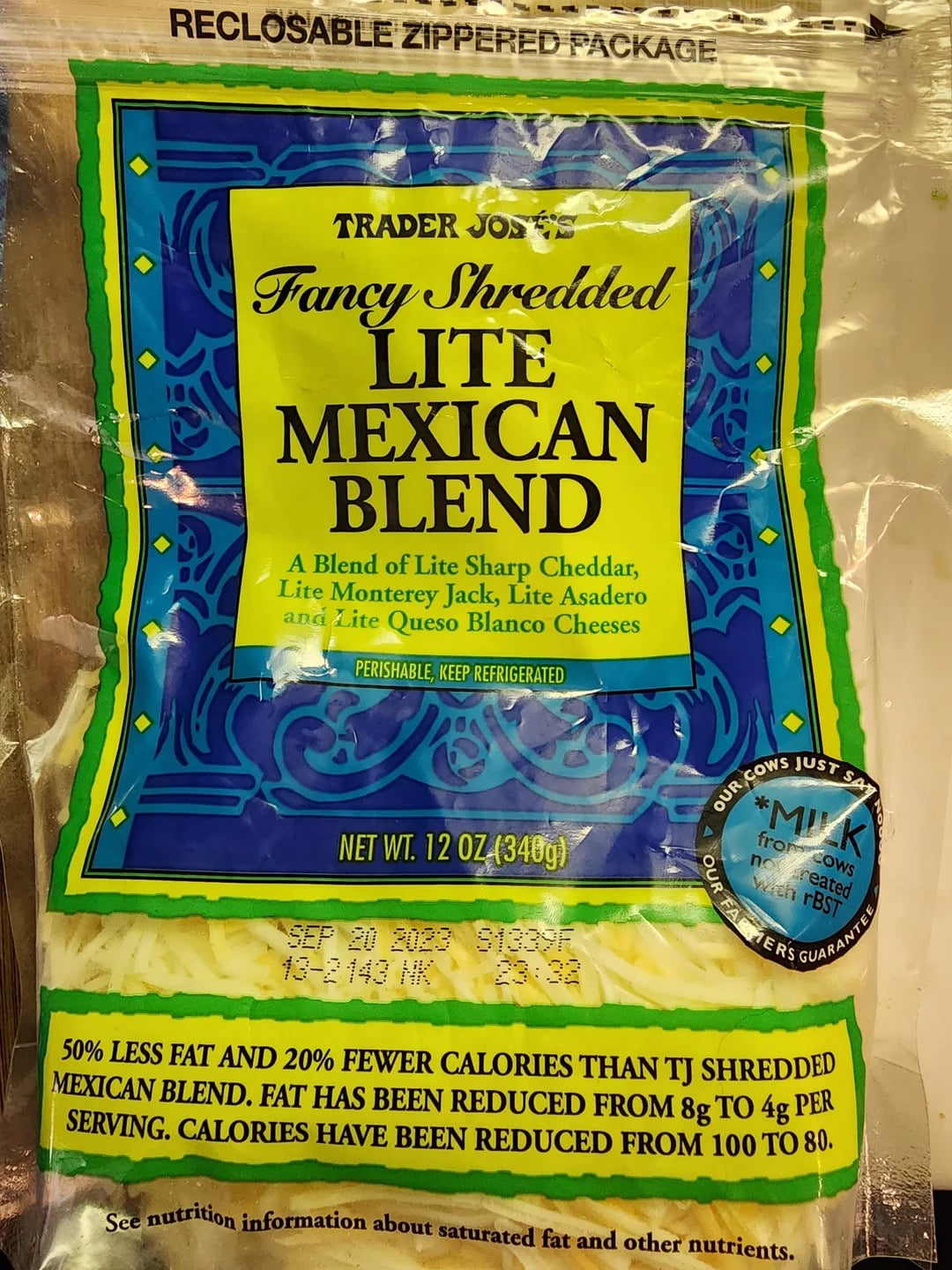 Trader Joe’s Lite Mexican Blend shredded cheese package features detailed product information and nutrition claims about reduced fat and calories, highlighted by a prominent label stating "50% less fat and 20% fewer calories" compared to regular Mexican blend cheese. This makes it a great choice for those seeking the best shredded cheese option without sacrificing flavor or quality.