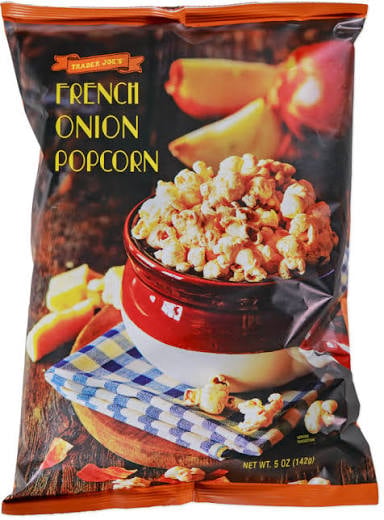 Bag of Trader Joe’s French Onion Popcorn with an image of popcorn in a red bowl, surrounded by cheese cubes and onions on a wooden surface with a checkered cloth.