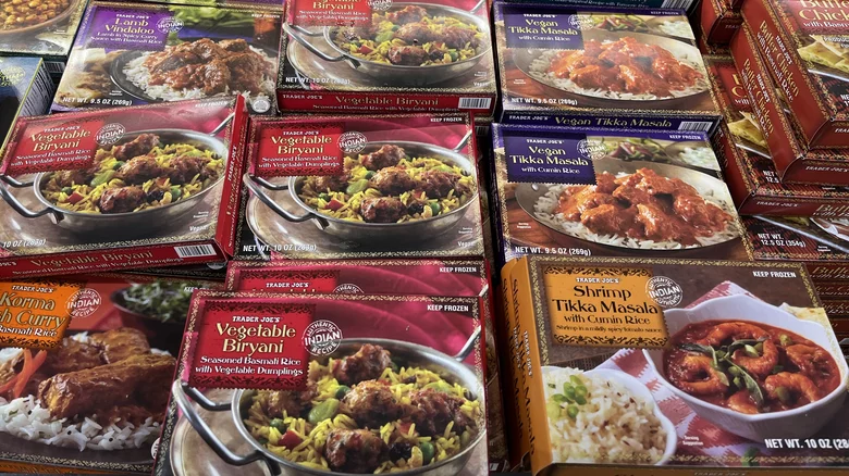 Assorted boxes of frozen Indian meals, including Vegetable Biryani, Vegan Tikka Masala, Shrimp Tikka Masala, and Vegetable Dumplings, are displayed on a store shelf.