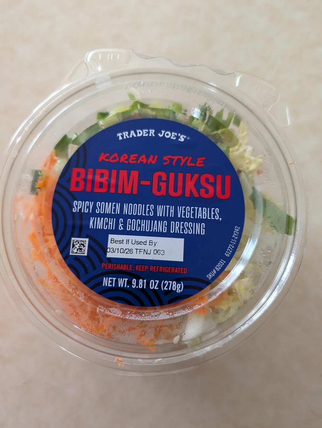 A container of Trader Joe's Korean Style Bibim-Guksu, labeled as spicy somen noodles with vegetables, kimchi, and gochujang dressing. The net weight is 9.81 oz (278g).