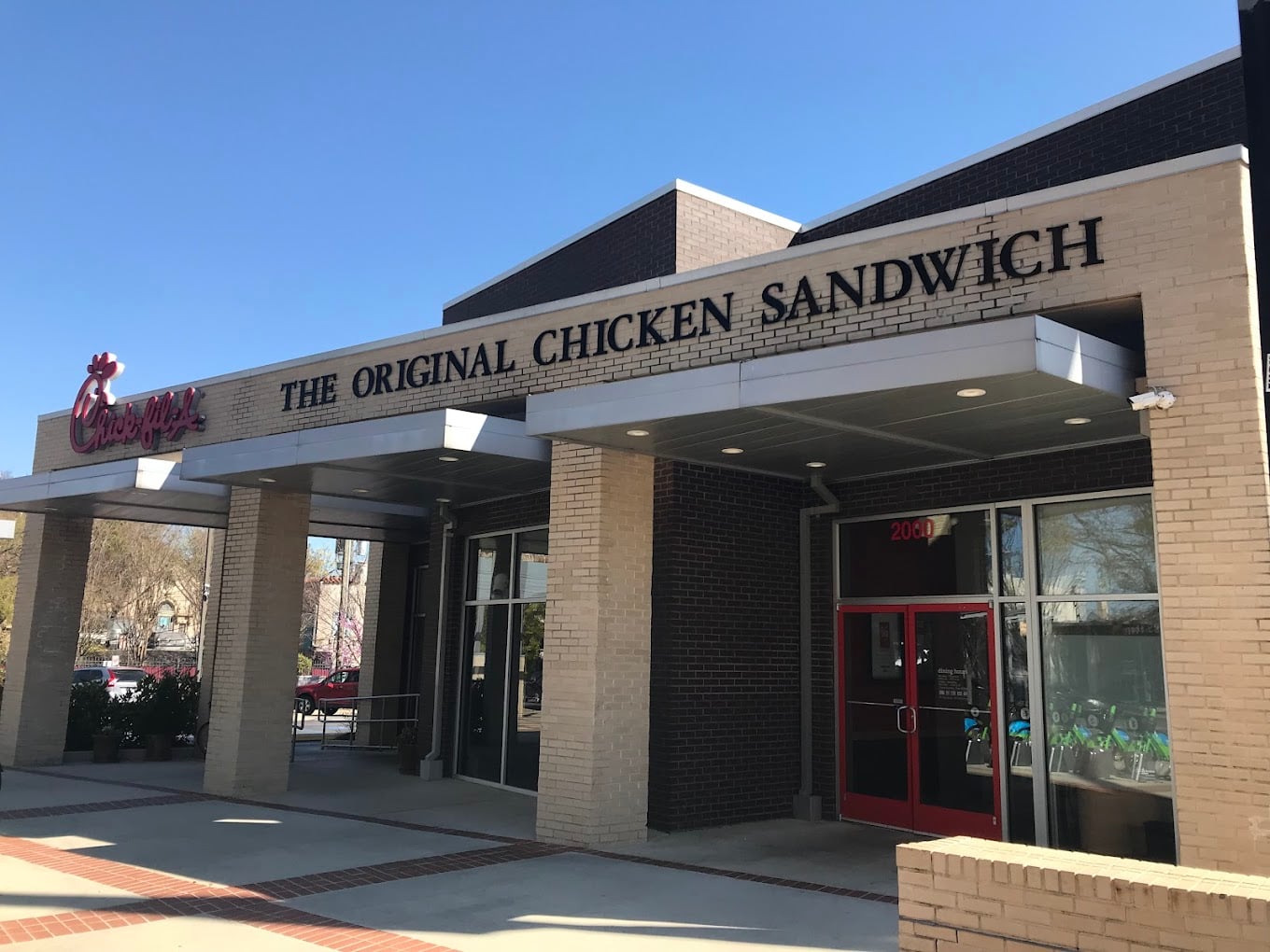Chick-fil-A restaurant exterior with a sign reading "The Original Chicken Sandwich" above the entrance, featuring tan and dark brick walls, large windows, and a red door—one of the favorite fast-food chains by state.