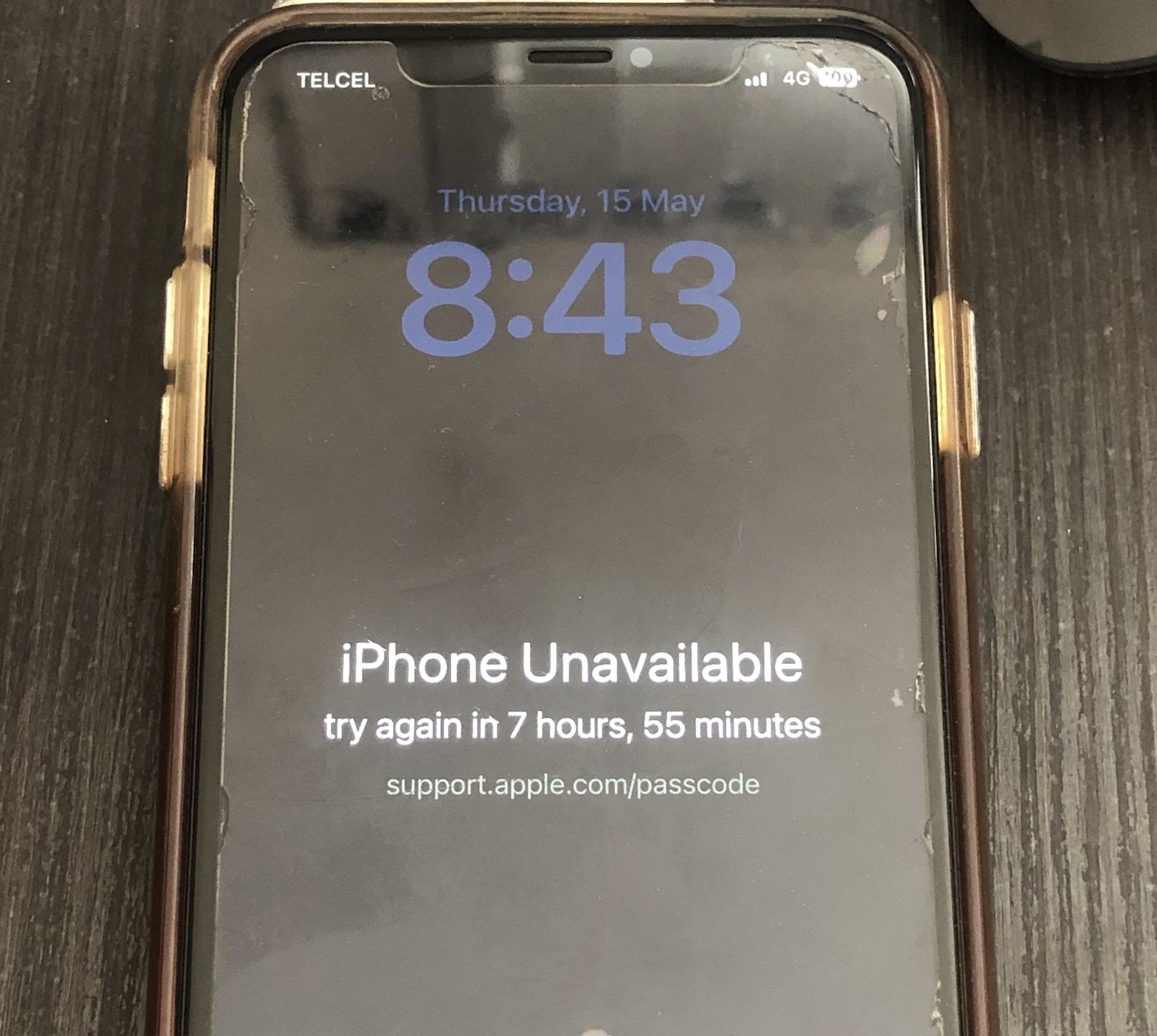 An iPhone screen displays “iPhone Unavailable, try again in 7 hours, 55 minutes” with a link to support.apple.com/passcode. The time is 8:43 on Thursday, 15 May.