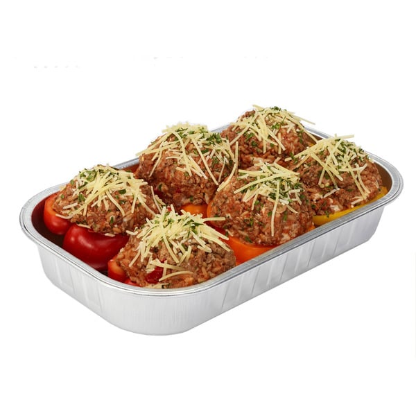 A foil tray filled with six stuffed bell peppers topped with shredded cheese and herbs, ready to be cooked.