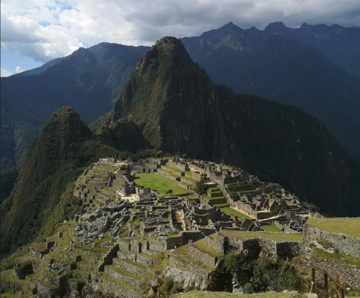Ancient stone ruins of Machu Picchu sit atop a lush mountain ridge, surrounded by green peaks under a cloudy sky in Peru, offering the kind of awe-inspiring beauty that often features in travel experiences that went viral.