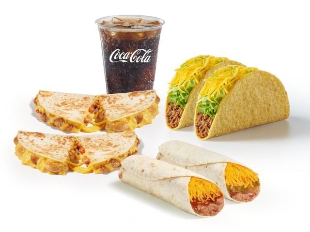 A fast food meal with a cup of Coca-Cola, two hard shell tacos with lettuce and cheese, a cheese quesadilla cut in half, and two soft tacos filled with meat and shredded cheese.