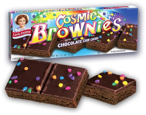 A box of Little Debbie Cosmic Brownies with two chocolate brownies topped with colorful candy-coated chips in front of the package.