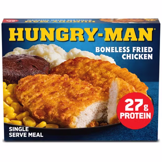 Box of Hungry-Man Boneless Fried Chicken meal with mashed potatoes, corn, and a brownie. A red label says “27g protein.” The packaging reads “Single Serve Meal” in white text. Frozen TV dinners.