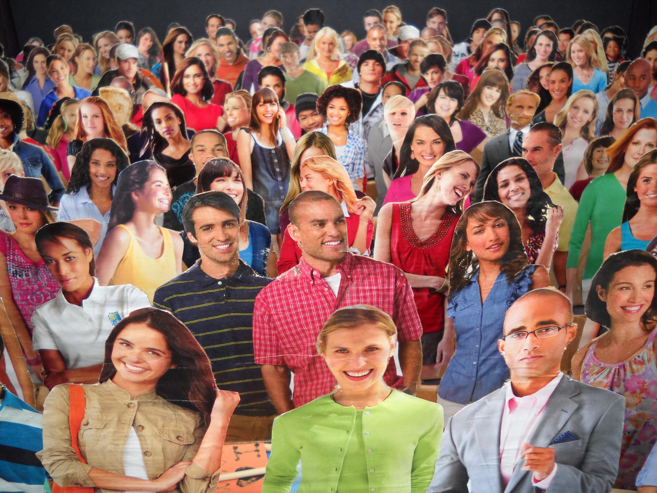 A crowd of diverse people, mostly smiling, stand closely together. They all appear to be cut-out images, overlapping in various poses, suggesting unity and diversity.