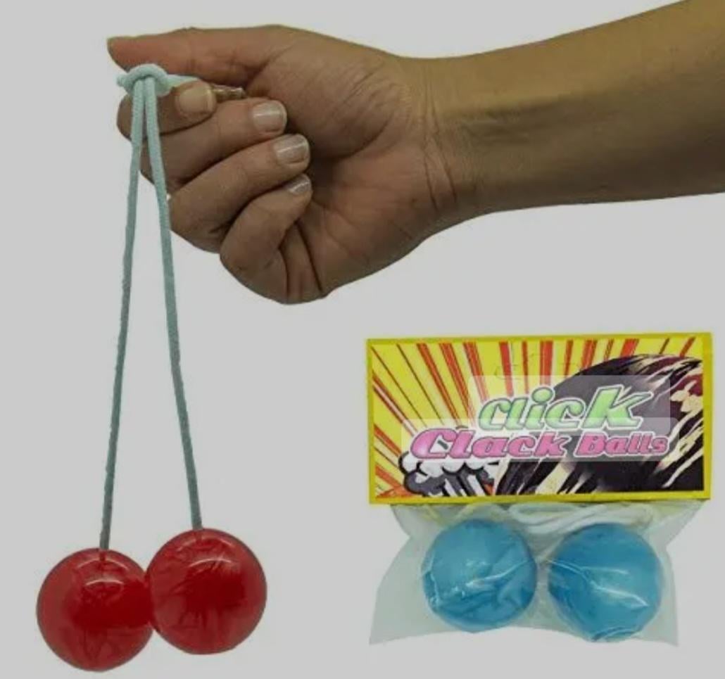 A hand holds two red clack balls connected by a string. Next to it is a package containing two blue clack balls labeled “Click Clack Balls.”