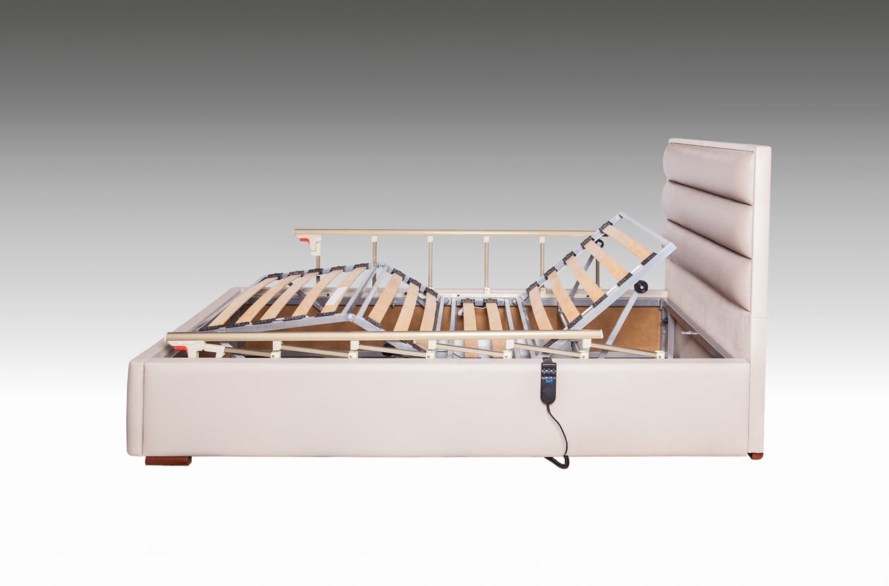 Side view of an adjustable beige bed with a padded headboard, reminiscent of the comfort and luxury from things hotels used to offer guests, showing the mattress base elevated at the head and foot sections with a remote control attached to the side.