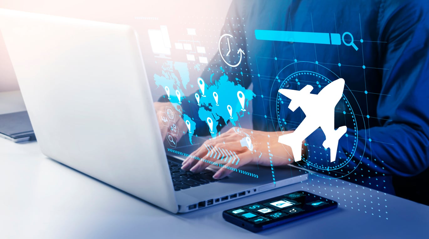 Person using a laptop with travel-related graphics, such as an airplane, a world map with location pins, and a smartphone on the table, symbolizing online flight booking or travel planning and reflecting modern travel behaviors.