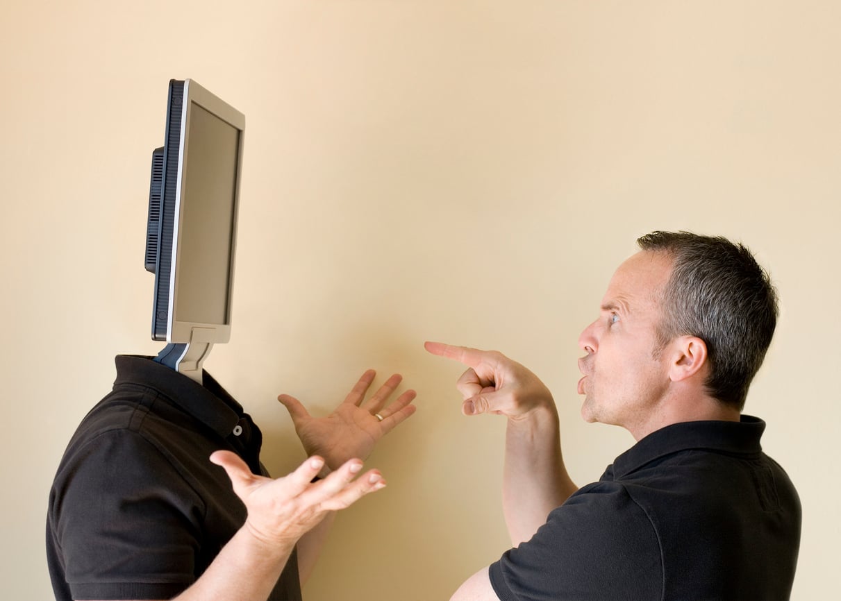 A man angrily points at another person whose head has been replaced by a computer monitor, while the second person shrugs in confusion.