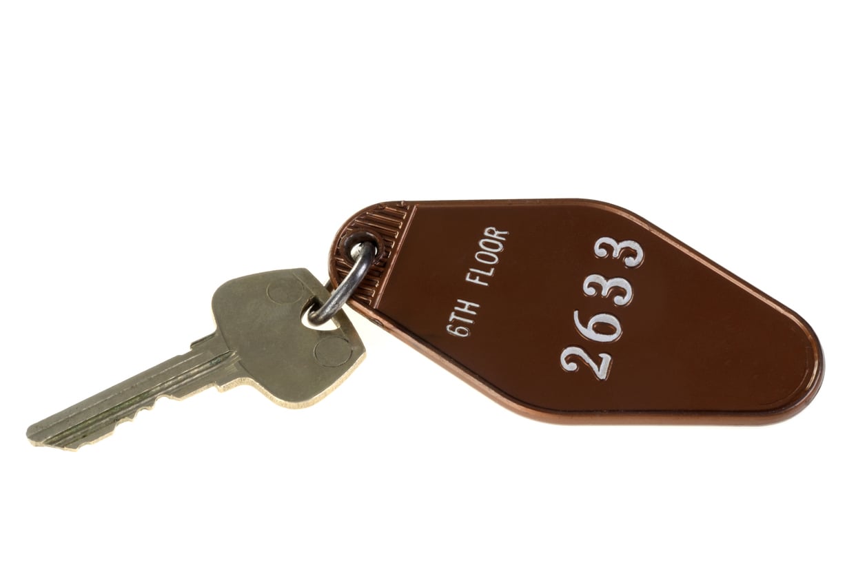 A single metal key attached to a brown key tag labeled “6th FLOOR 2633” in white letters, isolated on a white background—a classic example of the things hotels used to offer guests before the era of digital key cards.