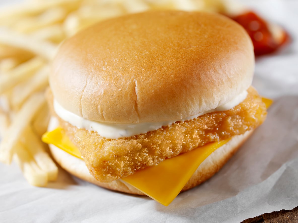 A fish sandwich with a slice of cheddar cheese and mayonnaise on a soft bun, served with French fries and a small portion of ketchup on the side—now that’s a meal that could star in some Wild Fast-Food Facts!