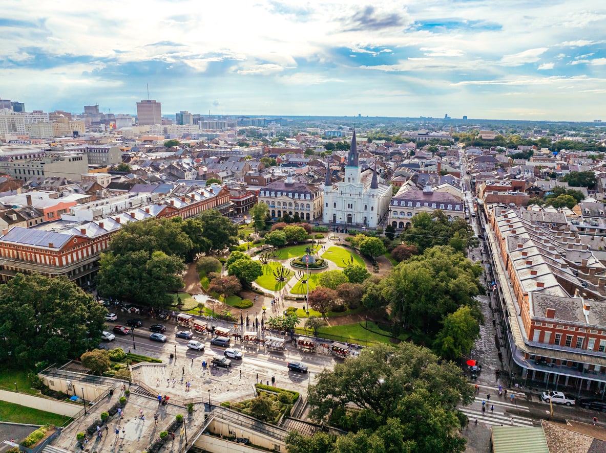 Aerial view of Jackson Square in New Orleans, showing St. Louis Cathedral, green park areas, and surrounding historic buildings under a partly cloudy sky—a stunning cityscape where visitors can enjoy vibrant culture and famous cuisine (though you’re just as likely to stumble upon bad food as you are incredible local flavors).