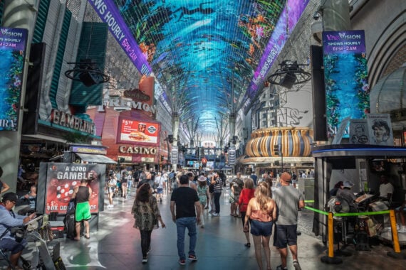 Crowds walk under the colorful LED canopy at Fremont Street in Las Vegas, surrounded by bright casino signs, shops, street vendors, and digital billboards. The atmosphere is busy and lively, offering a vibrant glimpse into the everyday excitement and energy that make up some of the most fascinating facts about Las Vegas.