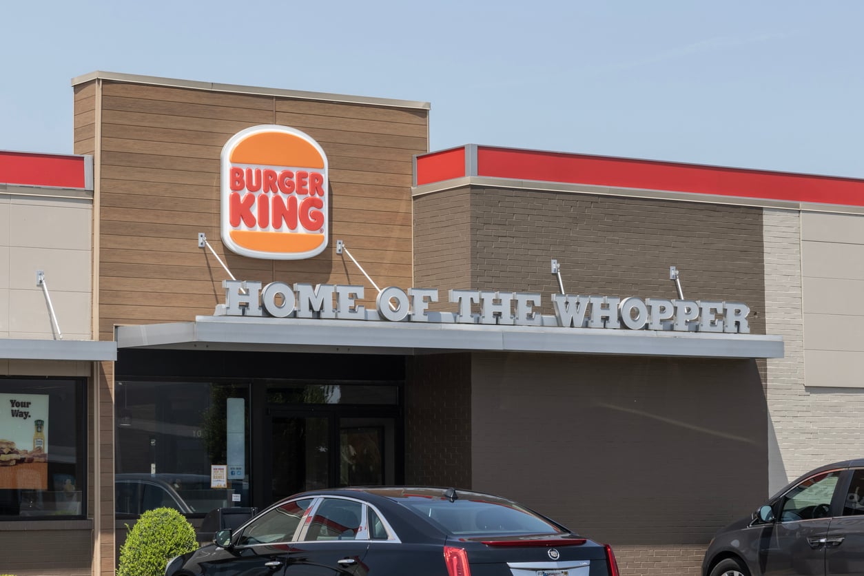 A Burger King restaurant exterior with the logo and a sign that reads “Home of the Whopper.” Several cars are visible in the parking lot in front of the building, hinting at just how popular this spot is for fans eager to enjoy some Wild Fast-Food Facts along with their meal.