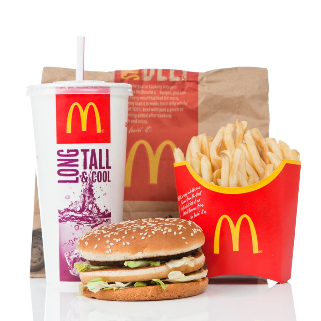 A McDonald’s meal with a burger, medium fries in a red container, a large soft drink cup with a straw, and a brown paper bag sits on a white background—perfect for anyone craving classic comfort and curious about Wild Fast-Food Facts.