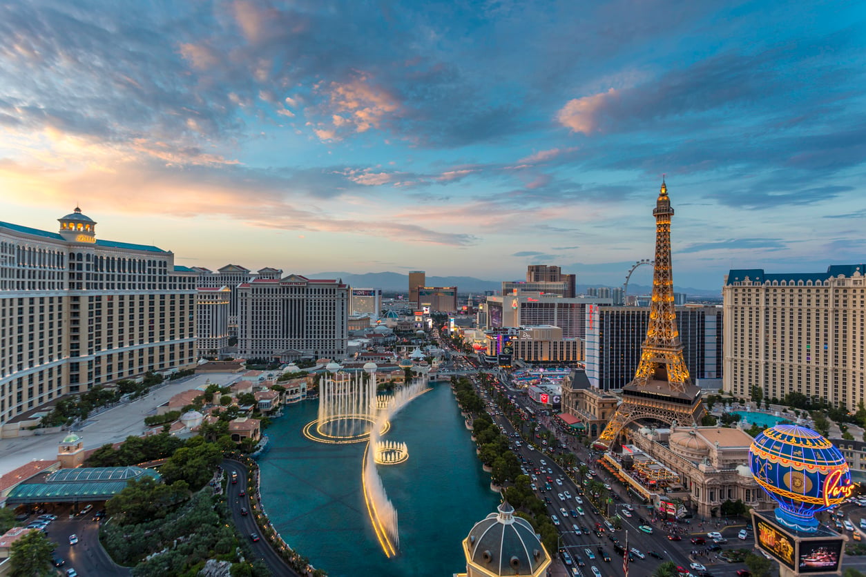 Aerial view of the Las Vegas Strip at sunset, featuring the Bellagio fountains, Paris Hotel’s Eiffel Tower replica, tall buildings, bright lights, and a busy street with cars—an iconic scene that highlights some fascinating facts about Las Vegas.