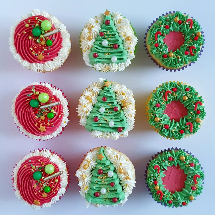 Nine festive cupcakes, perfect as homemade Christmas treats, are decorated with red, green, and white frosting. Some cupcakes feature Christmas tree designs, others have wreaths or are topped with colorful festive sprinkles. All are arranged in a 3x3 grid.