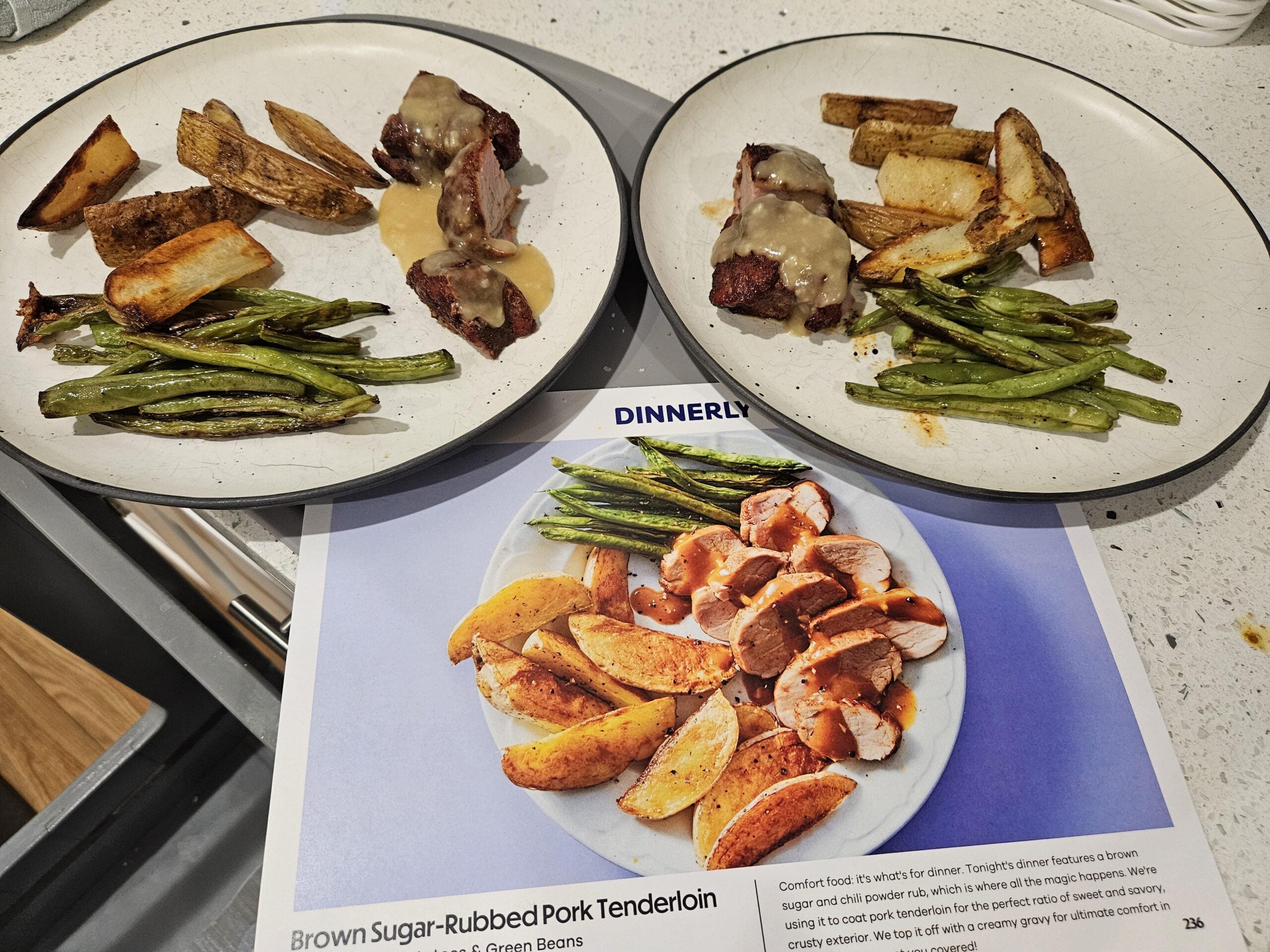 Two plates with pork, green beans, and potato wedges sit near a Dinnerly recipe card showing a similar meal: sliced pork, green beans, and potatoes on a white plate. Food portions differ from the card’s image.