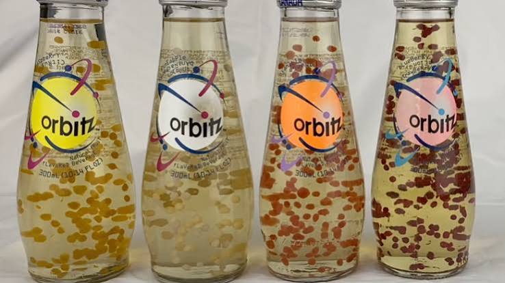 Four bottles of Orbitz drink with floating colored gel balls inside. Each bottle has a clear liquid and different colored balls, with the Orbitz logo on the front of the glass bottles.