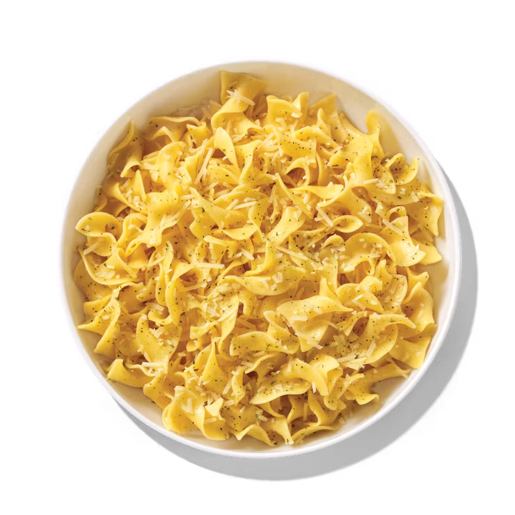 A white bowl filled with cooked egg noodles, lightly seasoned with black pepper, photographed on a plain white background.